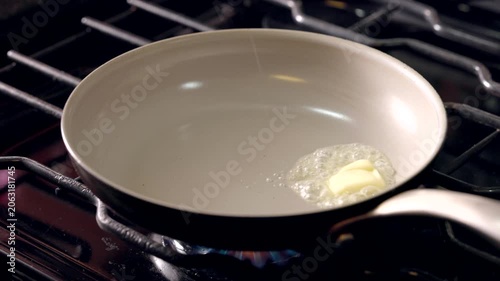 A pan with a piece of butter on it. The butter is melting and spreading out on the pan