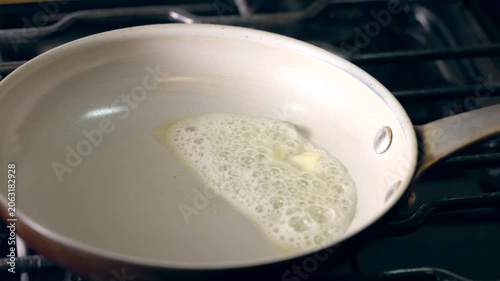 A pan with a piece of butter on it. The butter is melting and spreading out on the pan