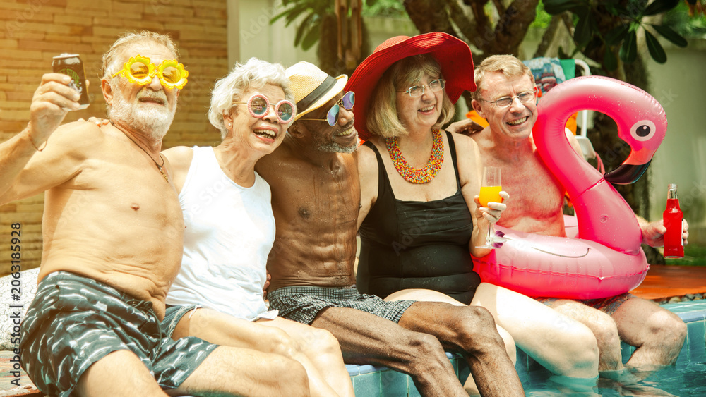 Obraz premium Seniors enjoying poolside fun with inflatable flamingo