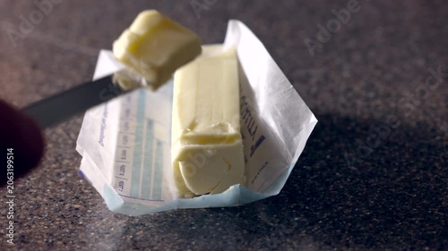 close up of a knife slicing a bar of butter for cooking in a home kitchen
