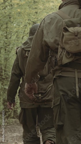 Group of Soldiers Marching In Forest. Historical Re-enactment. Re-enactors Dressed As American Soldiers Of USA Infantry Of World War II Marching Walking Along Forest Road In Autumn Day