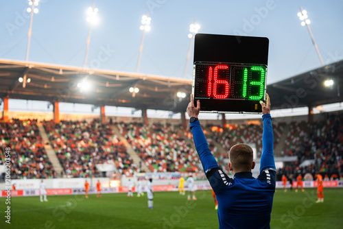 Fotografie Rear view of a fourth official holding an electronic substitution board showing numbers 16 and 13 at a football stadium