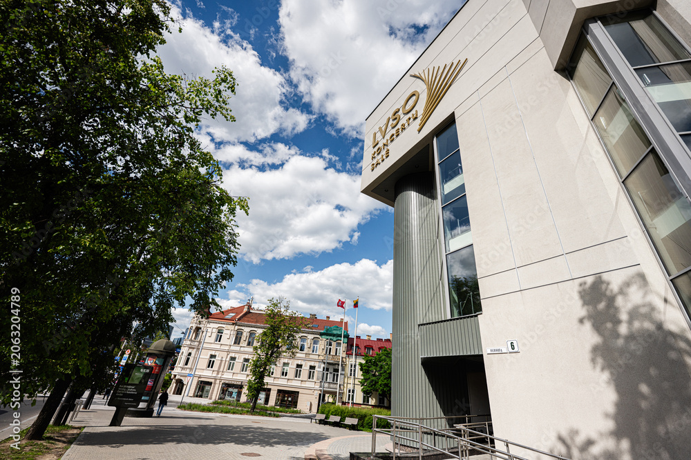 Naklejka premium Modern civic building with LVSO sign and columned facade in Vilnius, Lithuania city street scene with trees and blue sky