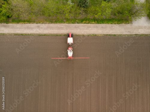 Aerial shot of a tractor fertilizing a agriculture crop fields