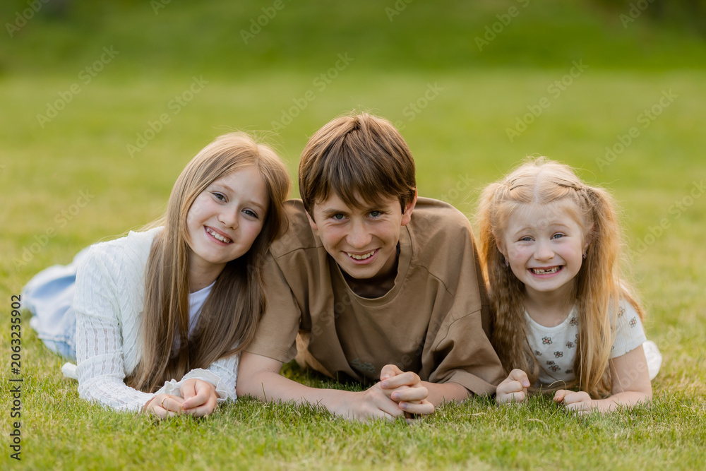 Fototapeta premium three children hugging on the lawn in the summer
