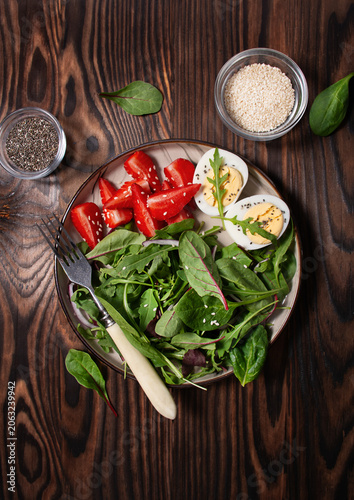 Balanced salad with green lettuce, strawberries, boiled eggs for lunch on a wooden table. Balanced nutrition. Top view.