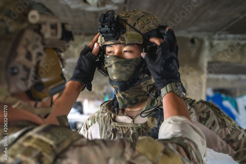 Fotografía Senior military soldier adjusting tactical head mounted action camera on younger