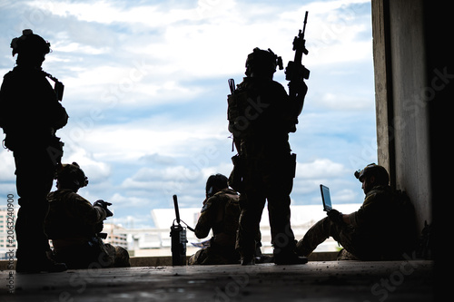 Bild auf Leinwand Silhouette special armed military squad team in full gear patrolling an abandone