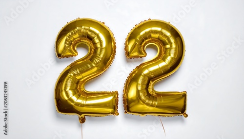 A gold-colored balloon in the shape of the number 22 on a white background
