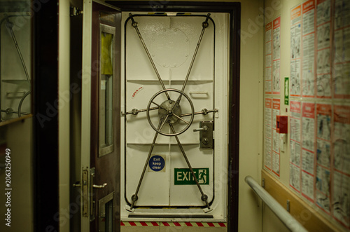 Принти на полотні Interior view of a marine watertight door fitted with a central wheel locking mechanism and emergency exit signage