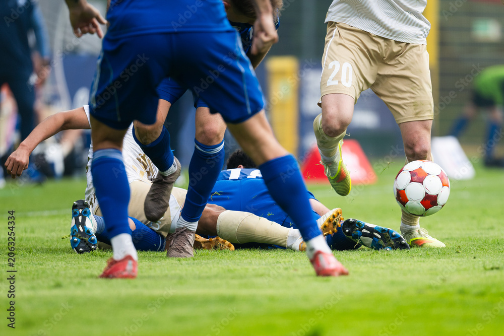 Naklejka premium Intense football challenge with players battling for the ball after a sliding tackle during a competitive soccer match