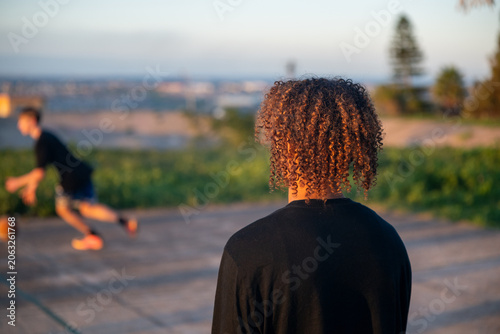 Young man with curly hair watching basketball game