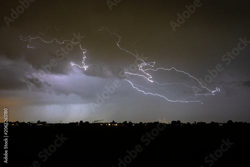 Dramatic night lightning streaks across a stormy sky above a dark horizon