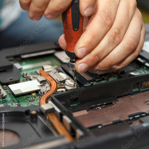 Close-up of a screwdriver working on a laptop motherboard. Focus on technology and repair