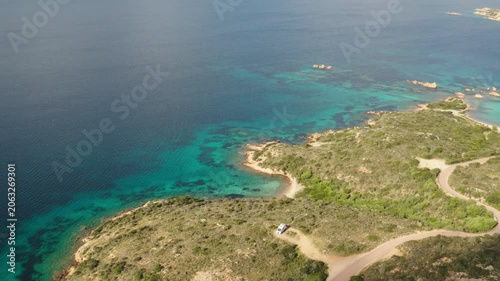 Ultra wide overhead drone shot of parked van on beautiful mediterranean island next to beach with clear turquoise blue water
