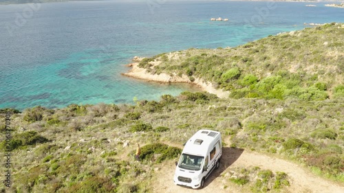 Drone flies over Camper van on mediterranean island while girl walks out to beach