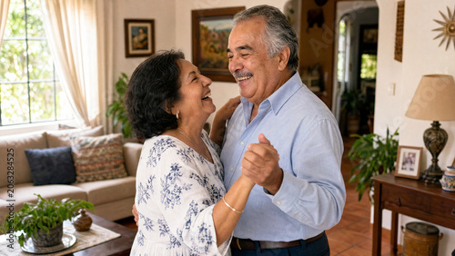 Senior Hispanic couple laughing affectionately while slow dancing together in their living room