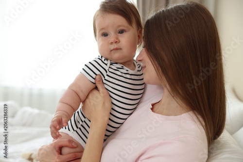 Vászonkép Happy mother with her cute little baby on bed at home