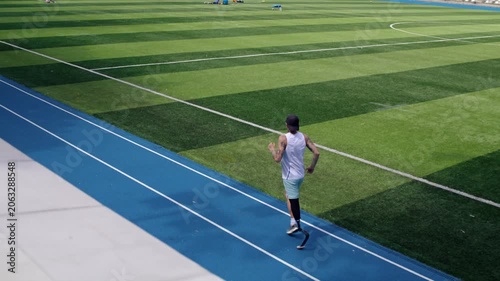 Paraathletic runner with bionic prosthetic leg trains at stadium