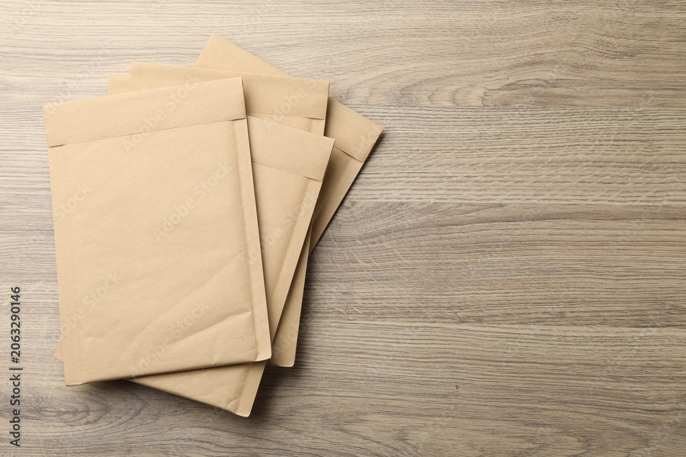 Obraz premium Stack of kraft envelopes on wooden table, top view. Space for text