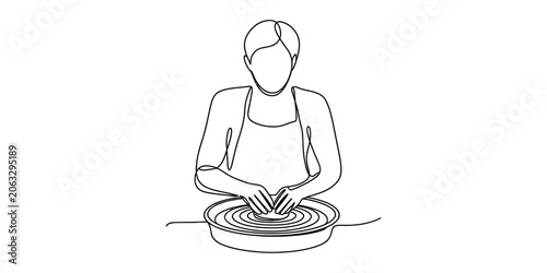 Person wearing an apron working on a pottery wheel with clay