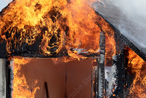 Fotografie A miniature house burns in a controlled manner to observe the behavior of different materials and untreated wood against fires