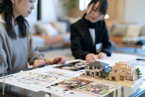 新築住宅の模型を前に不動産担当者と女性顧客が真剣に相談する