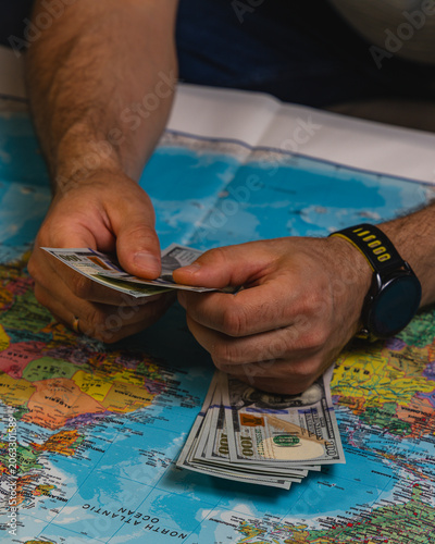 Planning travel budget on a world map with cash in hand for future trip