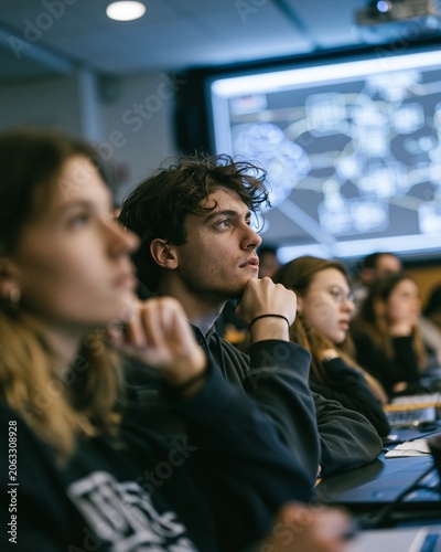 A university classroom of young adults exchange doubtful looks while AI diagrams glow on a projector screen, thoughtful mood, cool overhead lighting, diagonal composition.