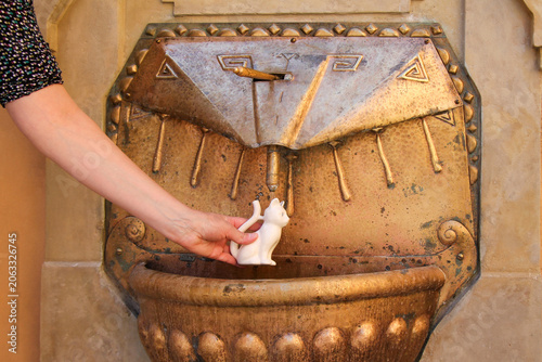 A woman fills a spa mug with mineral water from a spring.  Podebrady, Czech Republic.