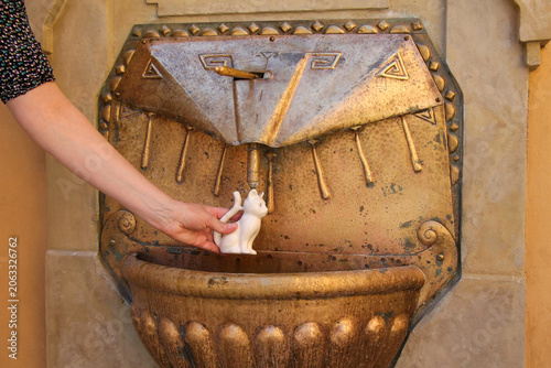A woman fills a spa mug with mineral water from a spring in spa town Podebrady, Czech Republic.