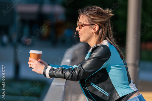 young woman enjoys takeaway coffee in the city