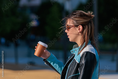 young woman enjoys takeaway coffee while walking in the city
