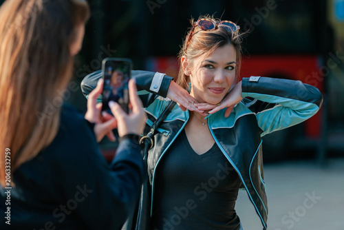 Young woman taking photo of friend with smartphone