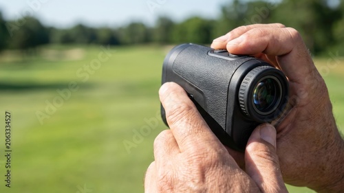 golfer hands holding laser rangefinder on the golf course