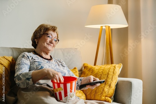 Senior woman enjoying popcorn watching tv at home