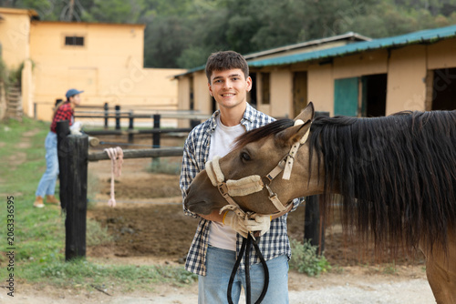 Obraz na plátně Portrait of guy of horse farm shows farm against the backdrop of corral for walk