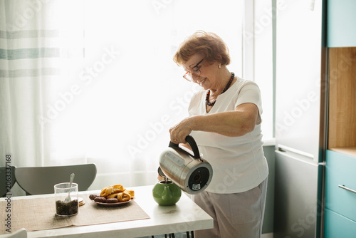 Happy senior woman preparing tea at home