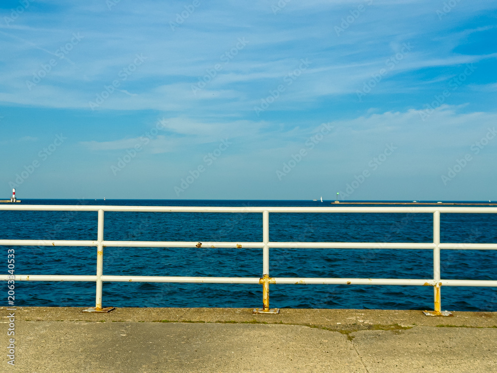 Fototapeta premium View of the ocean from a pier with a clear sky and boats on the water during the day