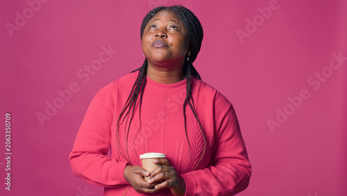 Foto Woman in thoughts looking up and holding cup of coffee, with female fashion blogger in contentment wearing pink sweater enjoys hot beverage