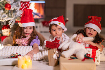Happy children play with soft fake snow by a window during a festive Christmas morning celebration indoors at home together.
