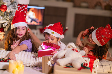 Happy children play with soft fake snow by a window during a festive Christmas morning celebration indoors at home together.