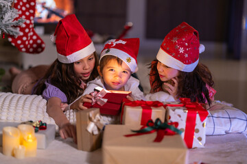 Happy children play with soft fake snow by a window during a festive Christmas morning celebration indoors at home together.
