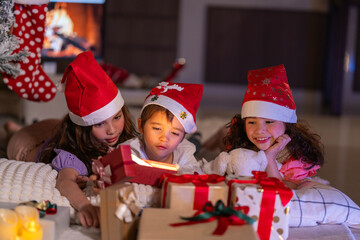 Happy children play with soft fake snow by a window during a festive Christmas morning celebration indoors at home together.