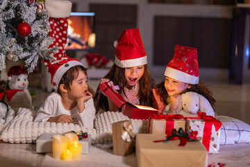 Happy children play with soft fake snow by a window during a festive Christmas morning celebration indoors at home together.
