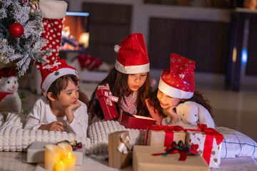 Happy children play with soft fake snow by a window during a festive Christmas morning celebration indoors at home together.