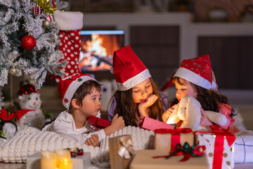 Happy children play with soft fake snow by a window during a festive Christmas morning celebration indoors at home together.