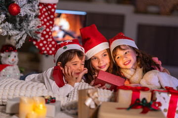 Happy children play with soft fake snow by a window during a festive Christmas morning celebration indoors at home together.