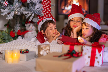 Happy children play with soft fake snow by a window during a festive Christmas morning celebration indoors at home together.