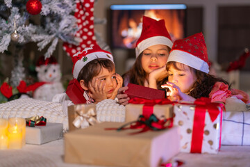 Happy children play with soft fake snow by a window during a festive Christmas morning celebration indoors at home together.
